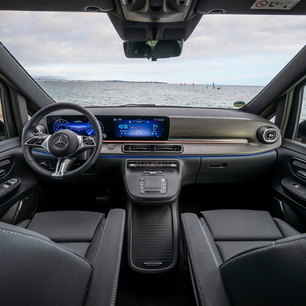 Mercedes-Benz EQV Armaturenbrett Ansicht aus dem Heckbereich des Fahrzeugs nach vorne schauend. Im Hintergrund durch die Frontscheibe sieht man das Meer.