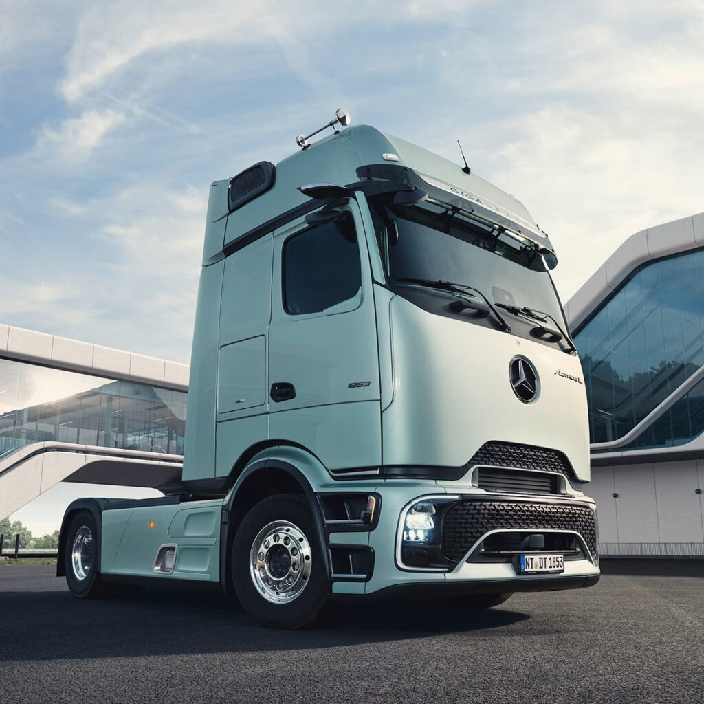 Actros L für Fernverkehr in weiss steht vor einem futuristischen Gebaeude